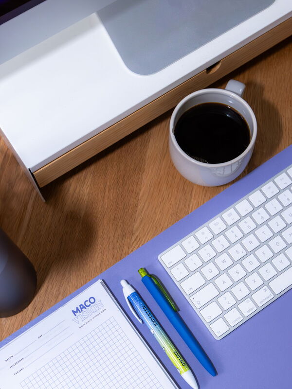 Schreibtisch mit Tastatur, Notizblock, Stiften und Kaffeetasse