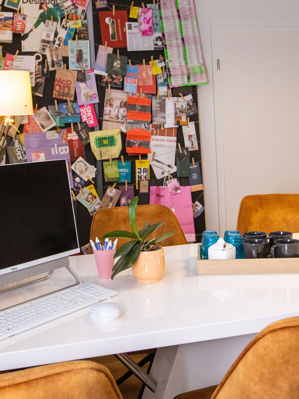 Ein Schreibtisch mit einem Computer, einer Tastatur, einer Maus, einem Stifteköcher und einer Pflanze